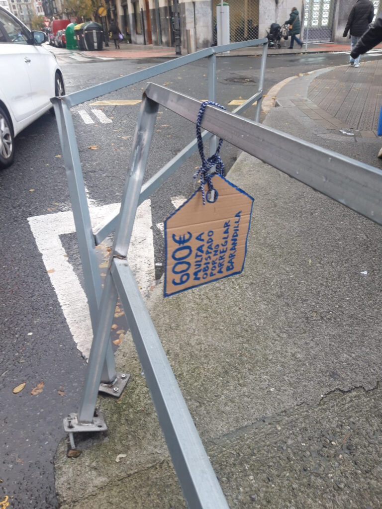 Recordatorio de multa con una etiqueta de cartón para visibilizar en la barandilla caída el problema.