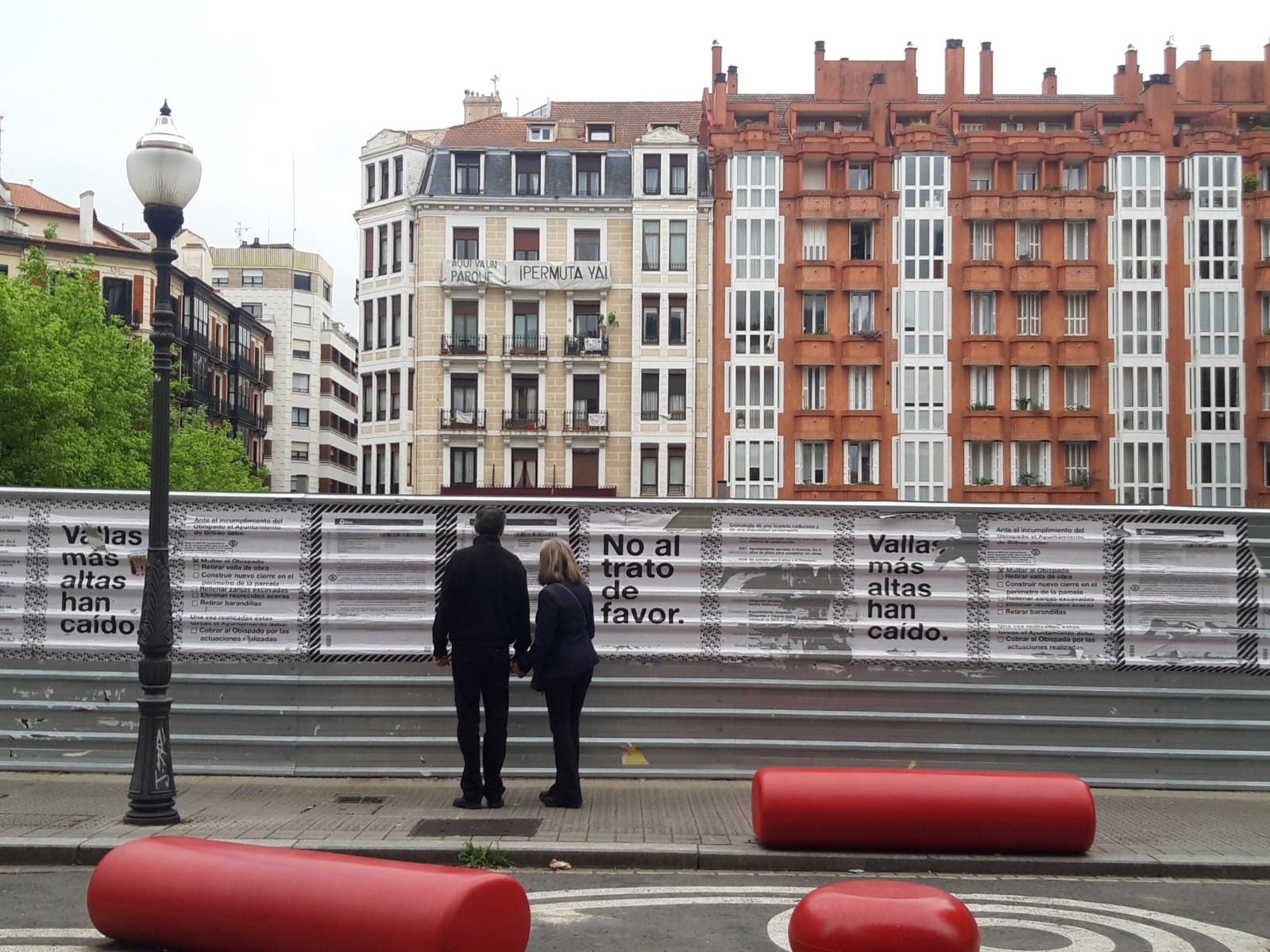 Transeuntes leen los carteles en la valla de obra de Obispado y Mutualia.